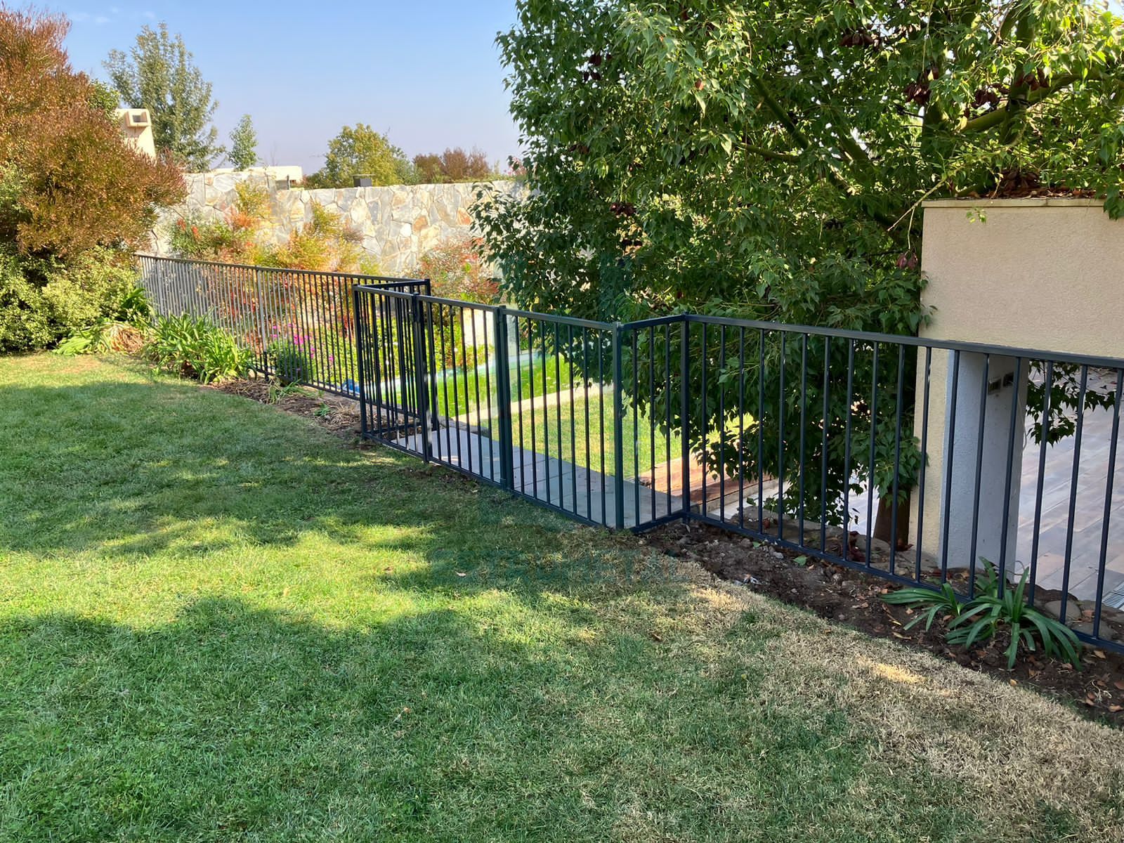 Reja tradicional para piscina, son barras verticales y horizontales por ambos lados de metal, protege a niños y mascota. Se instalo al borde de un desnivel teniendo como acceso por una escalera.